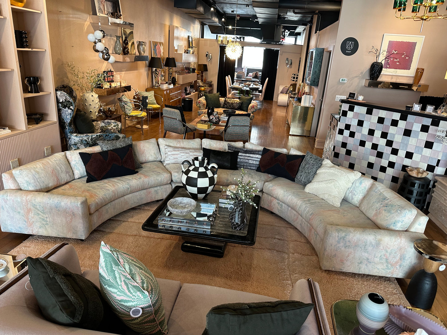 Vintage curved sofa by The Vault Creative featuring plush upholstery and elegant wooden legs in a stylish living room setting.