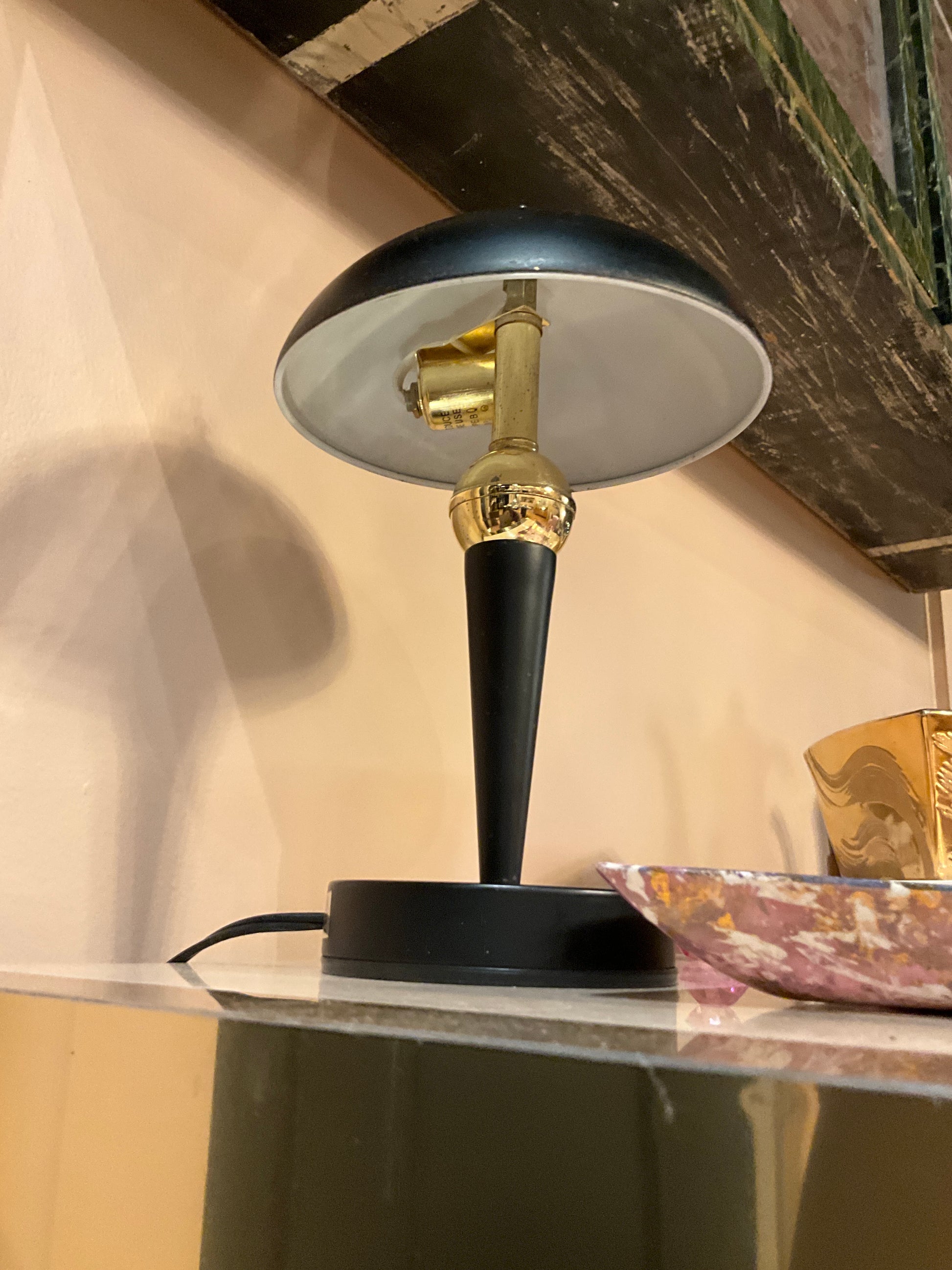 Small black metal table lamp with a sleek modern design, featuring a round base and adjustable arm from The Vault Creative.