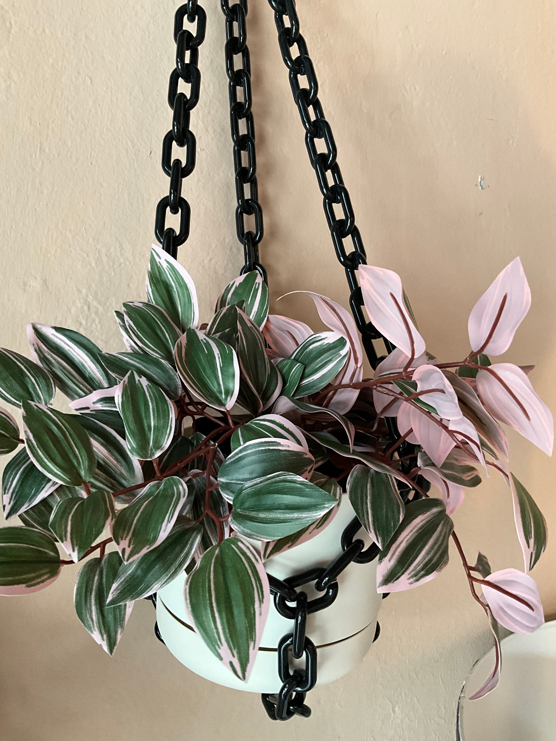 Black chain hanging planter by The Vault Creative with a round container and sturdy chain for indoor or outdoor plant display.