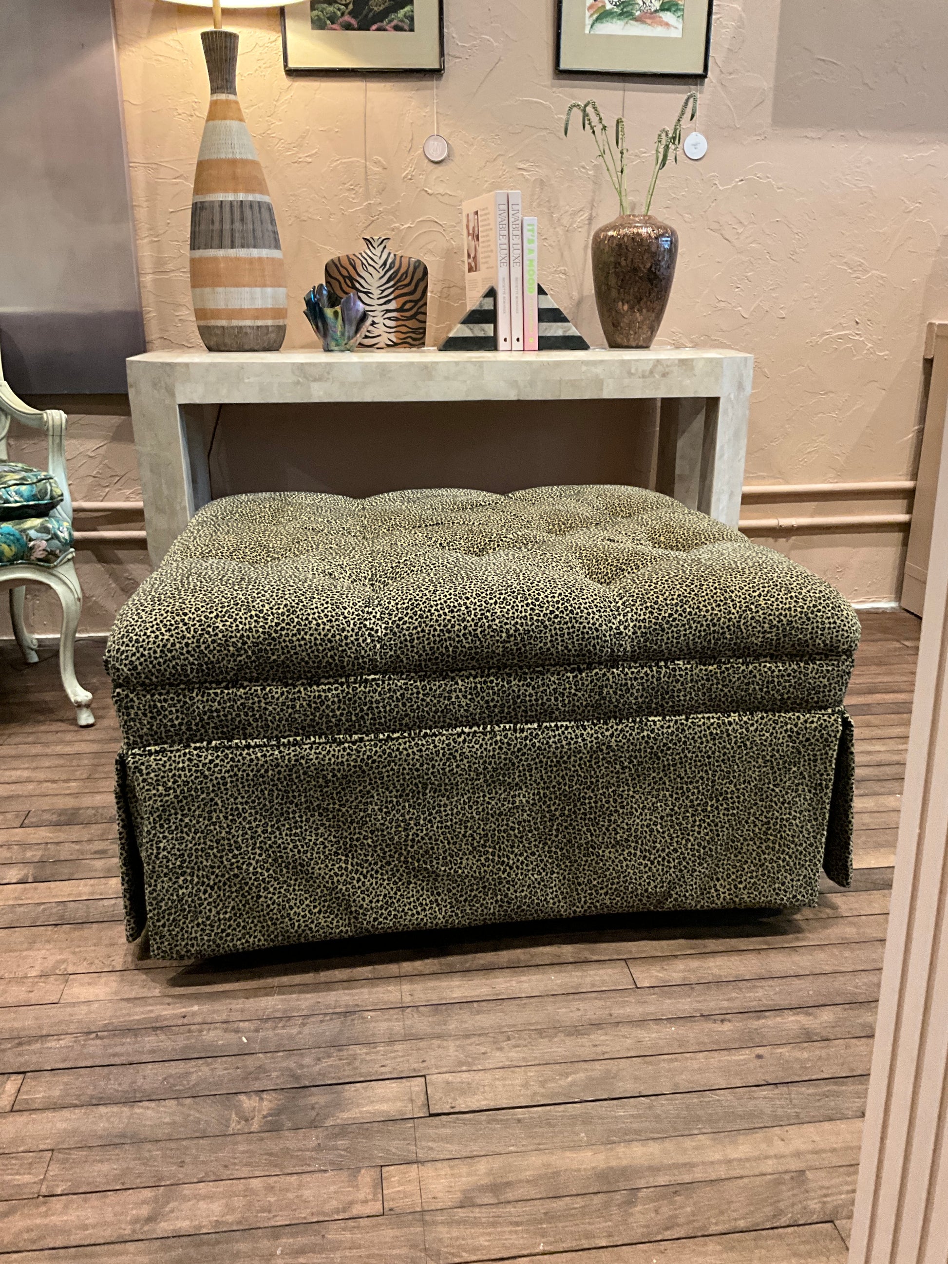 Square leopard ottoman by The Vault Creative with bold leopard print fabric and sturdy wooden legs.