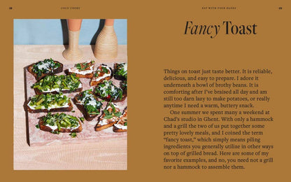 Open cookbook titled "Colu Cooks: Easy Fancy Food" by Abrams, displaying colorful recipes and culinary tips on pages.