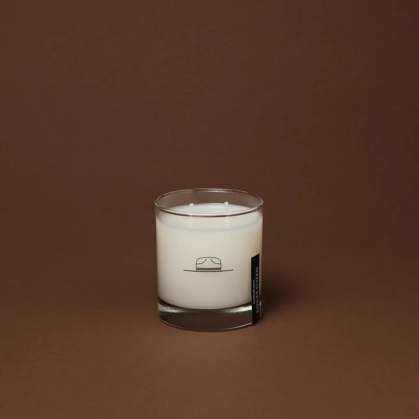 Ozmun Home Superbloom Candle in a glass jar with colorful floral design and a lit wick, creating a cozy and inviting ambiance.