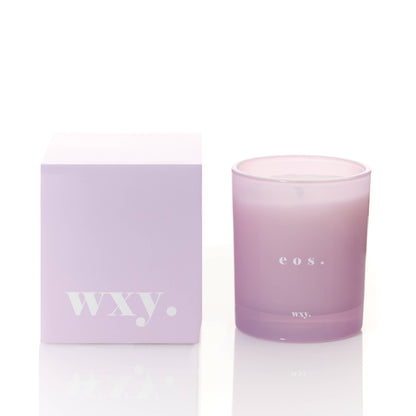 WXY eos 7oz candle featuring Orris Root and Amber scent in a glass jar with a lit wick and decorative packaging.