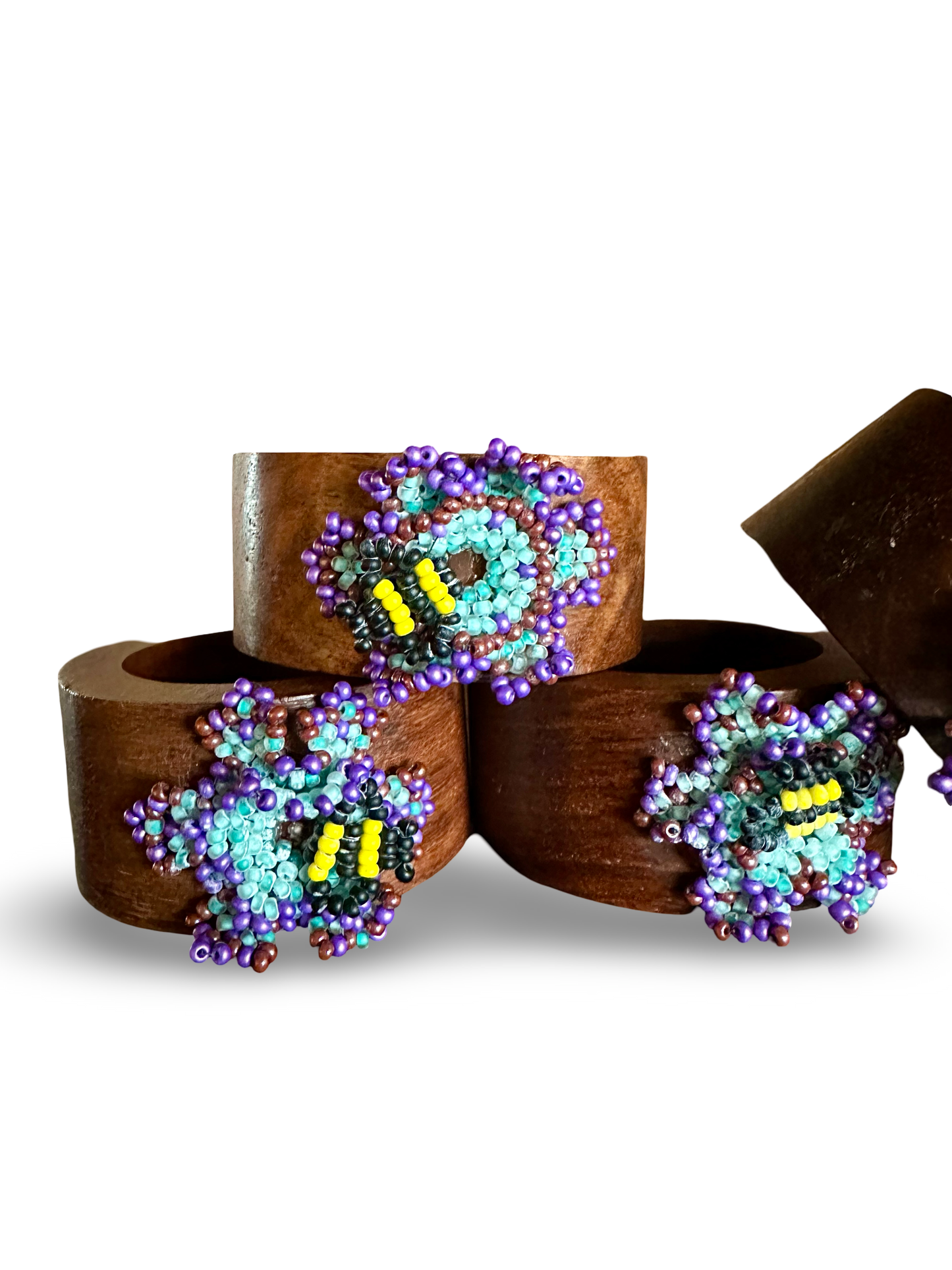 Six handmade bee-shaped napkin rings by Phoebe, crafted from wood with detailed bee designs for elegant table decor.