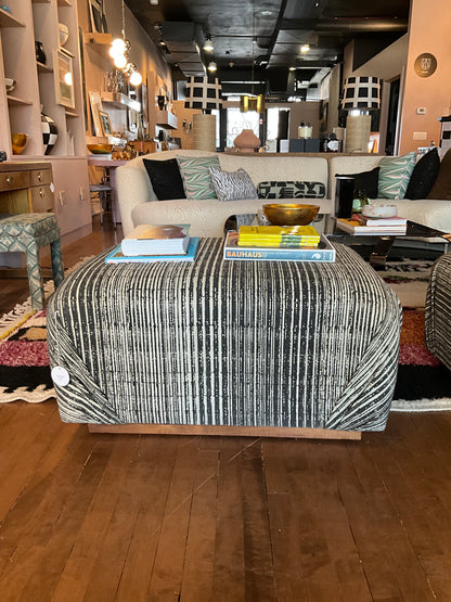 Vintage Ottoman Coffee Table by The Vault Creative with carved wooden legs and upholstered fabric top.
