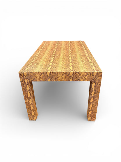 Vintage custom snakeskin coffee table from The Vault Creative with a textured snakeskin surface and wooden legs.