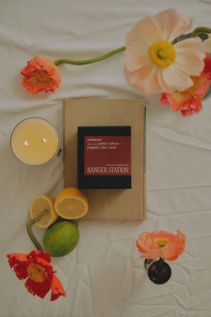 Ozmun Home Superbloom Candle with floral design and natural wax in a clear glass jar, perfect for home decor and ambiance.