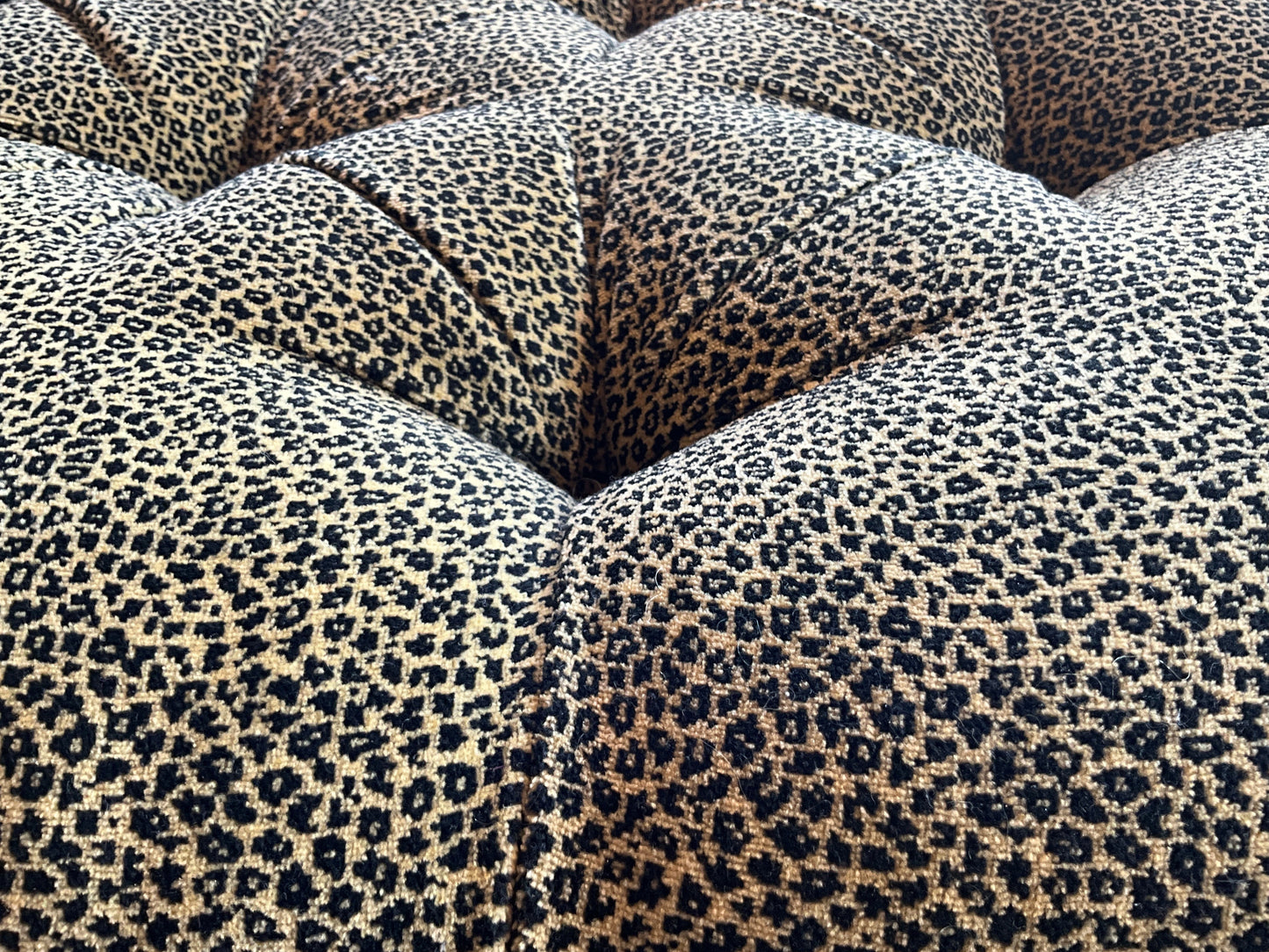Square leopard print ottoman by The Vault Creative, featuring a plush fabric surface and sturdy wooden legs.