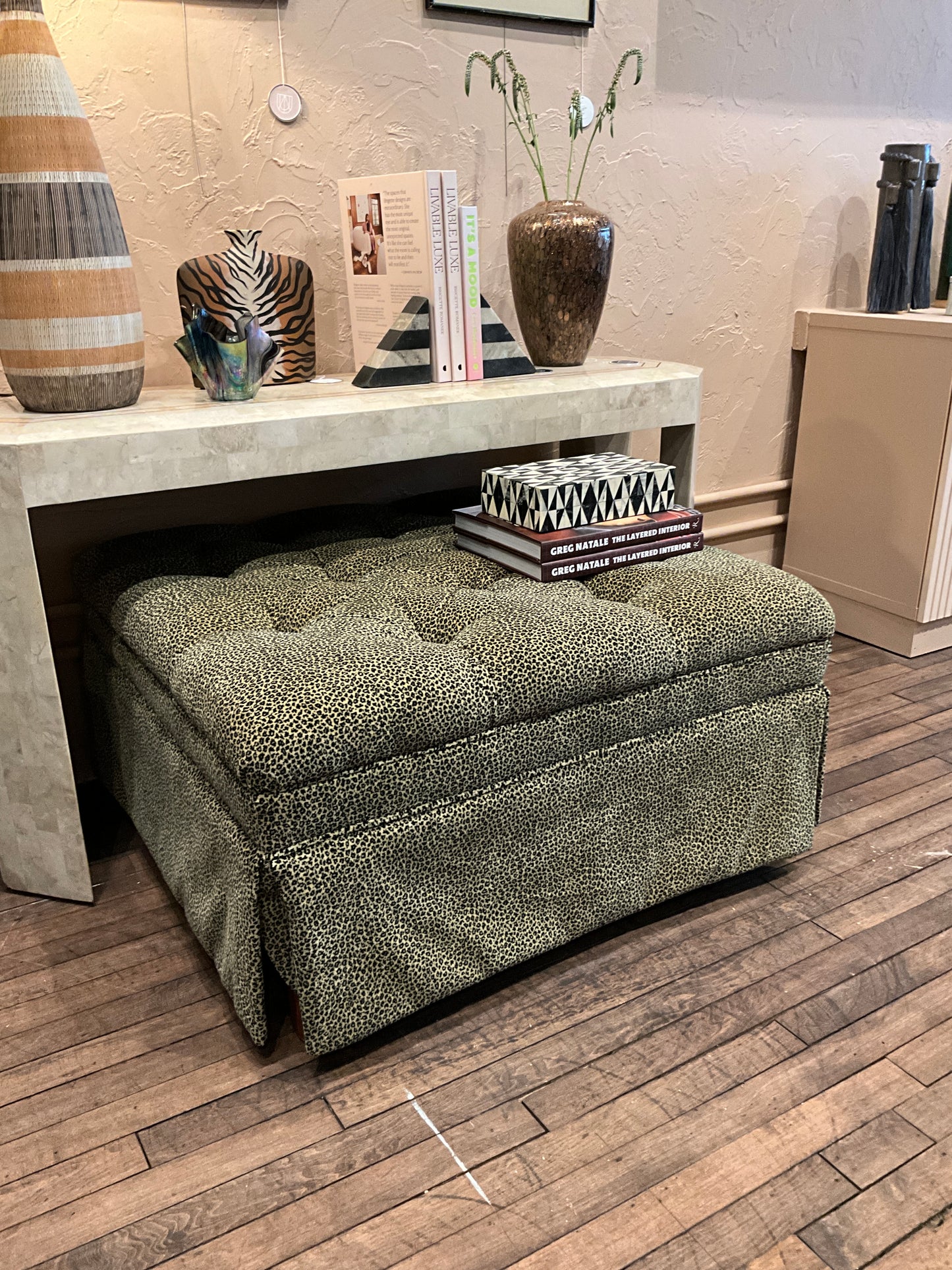 Square leopard-patterned ottoman by The Vault Creative, showcasing a stylish upholstered piece with a bold animal print design.