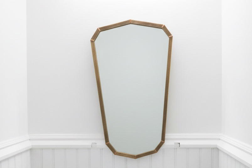 Vintage brass shield mirror with ornate frame, decorative wall mirror for classic or antique-style interior decor.