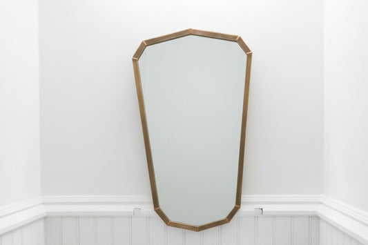 Vintage brass shield mirror with ornate frame, decorative wall mirror for classic or antique-style interior decor.