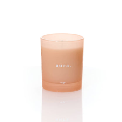 White Woods and Amber Aura 7oz candle by wxy in a sleek glass jar with a lit wick, emitting warm, inviting glow.