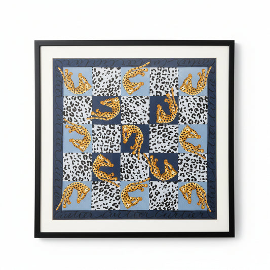 Framed Cartier scarf displayed on a wall, showcasing intricate design and luxurious fabric, in a stylish gold frame.
