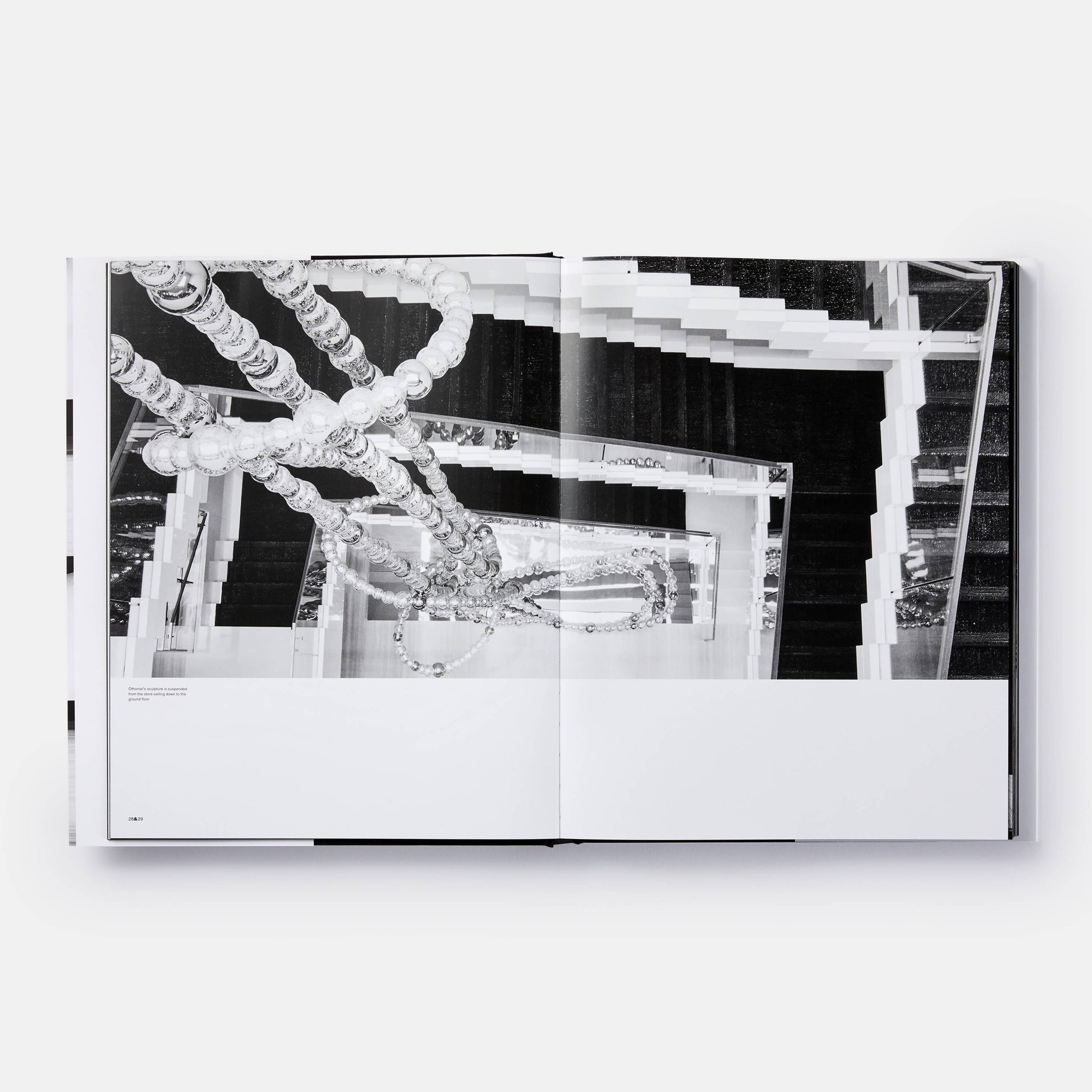 Open book titled "The Architecture of Chanel" by Phaidon showing black-and-white interior images and architectural sketches.