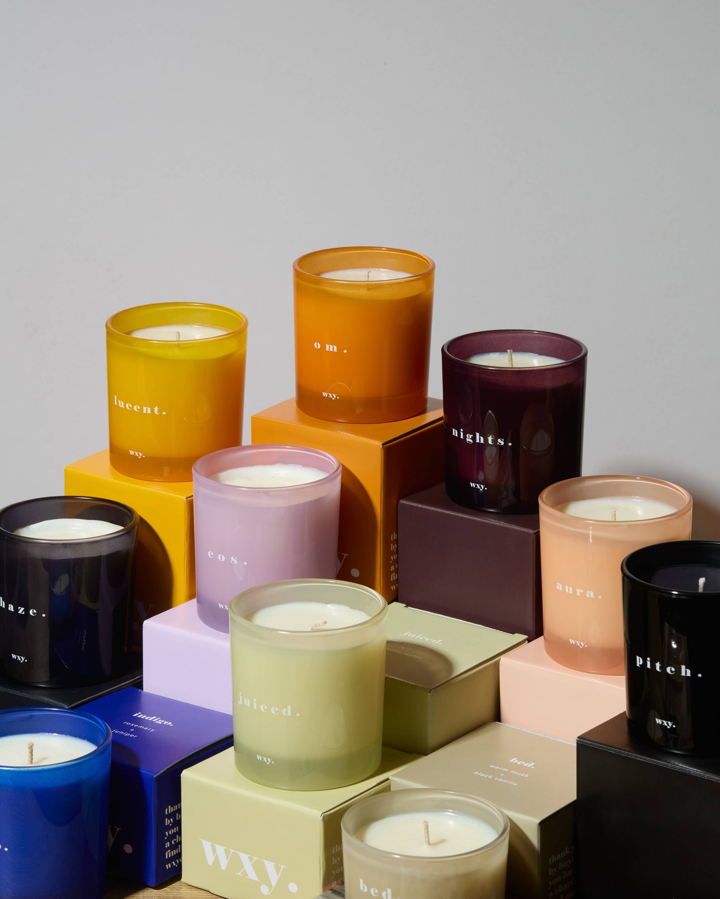 WXY EOS 7oz candle with Orris Root and Amber scent, featuring a white wax candle in a clear glass jar.
